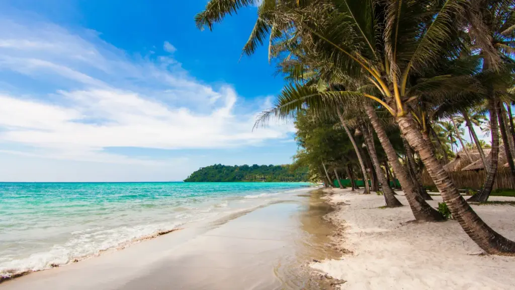 Een laagstaande zon kleurt de hemel boven de zee bij Ko Chang, met eilandjes in de verte en groen op de voorgrond.