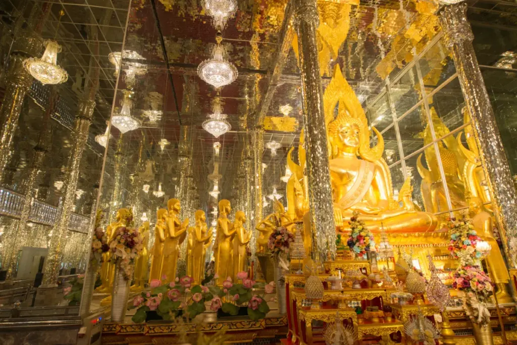 Grande statue dorée de Bouddha dans la salle aux miroirs du Wat Tha Sung, entourée de colonnes scintillantes.