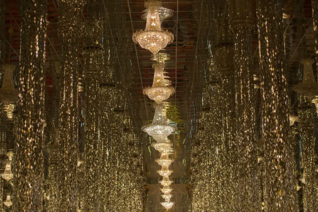Een rij kristallen kroonluchters tussen de spiegelende zuilen in de beroemde zaal van Wat Tha Sung.