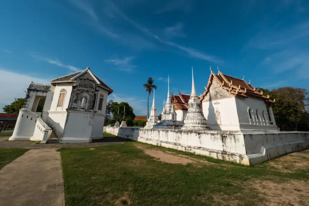 Witte tempelgebouwen en chedi's van Wat Uposatharam, met rijkversierde Thaise daken.